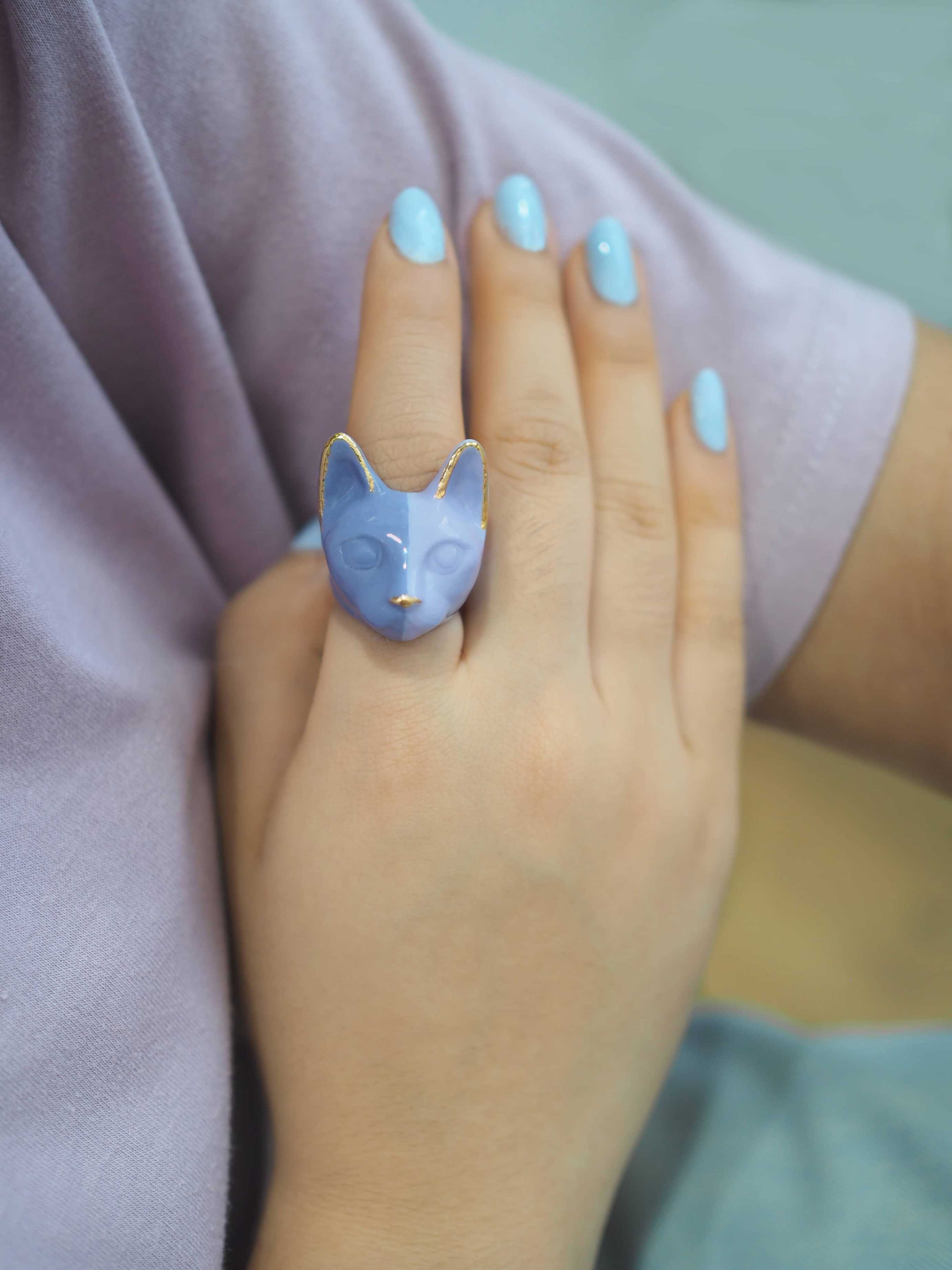 A handmade purple cat ring showcased on a hand with light blue nails.