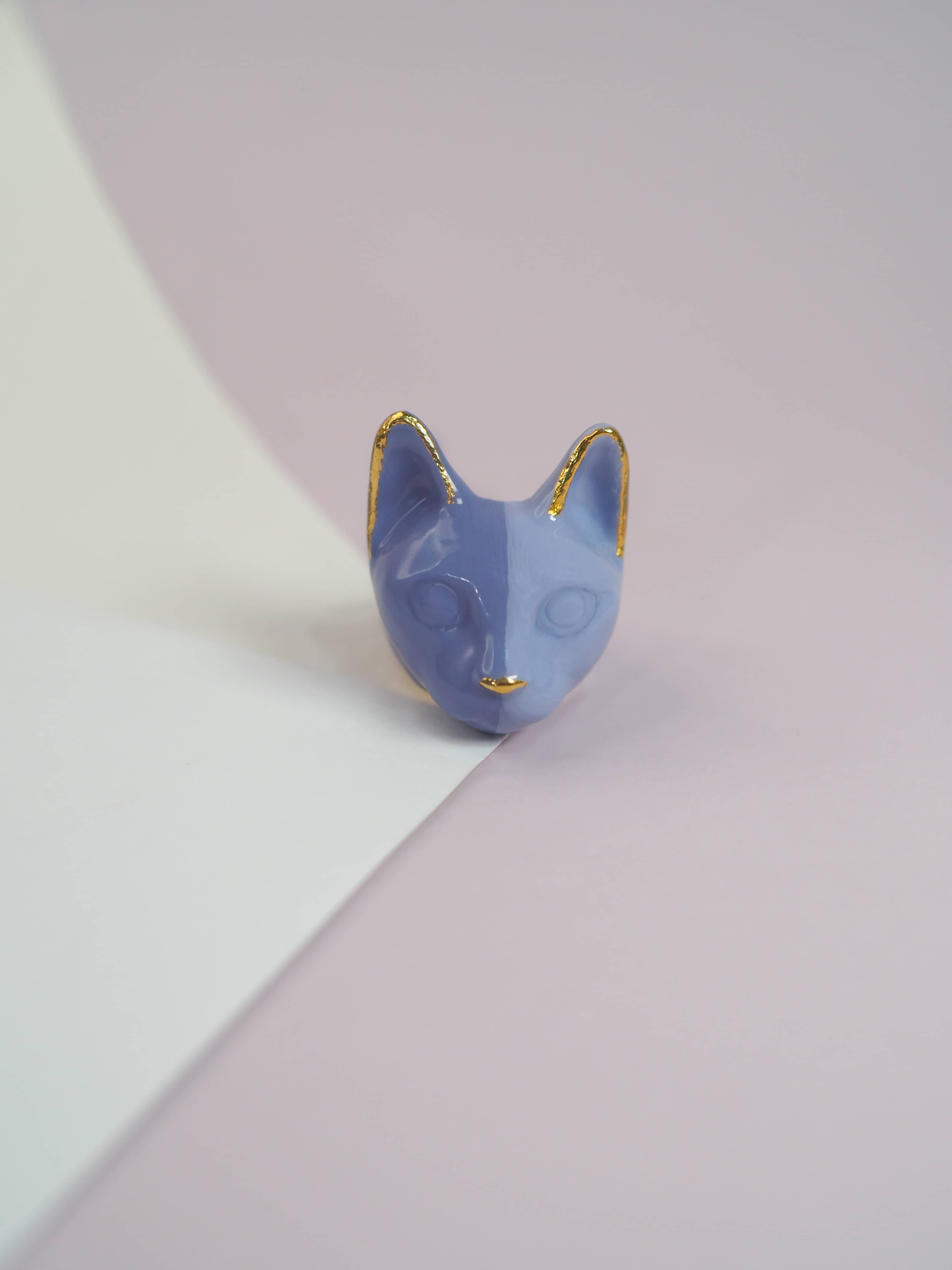 Whimsical lavender-themed cat ring design placed on pastel background.