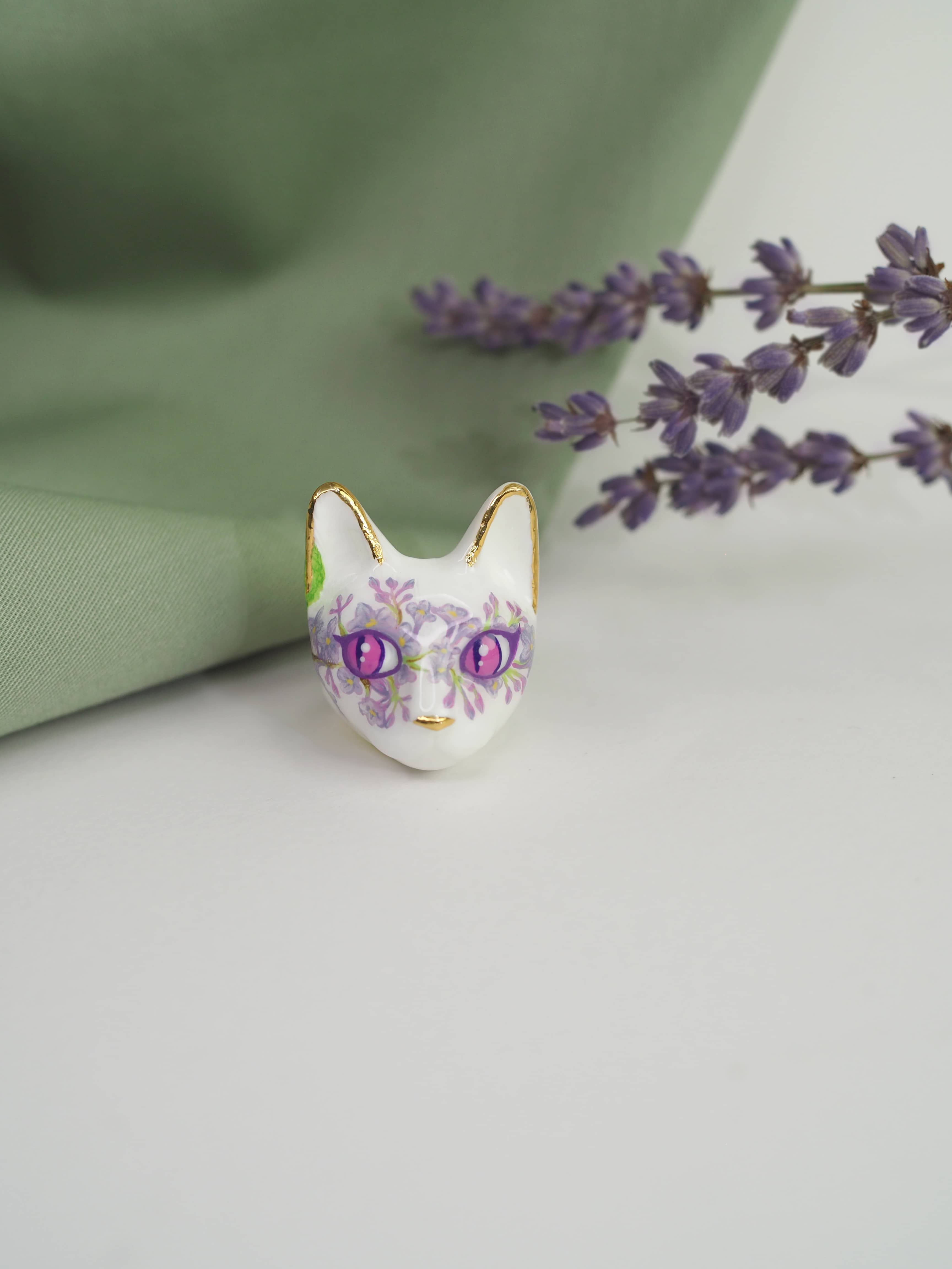 A beautiful cat rings with floral lilac patterns placed against a soft green background, alongside sprigs of lavender.