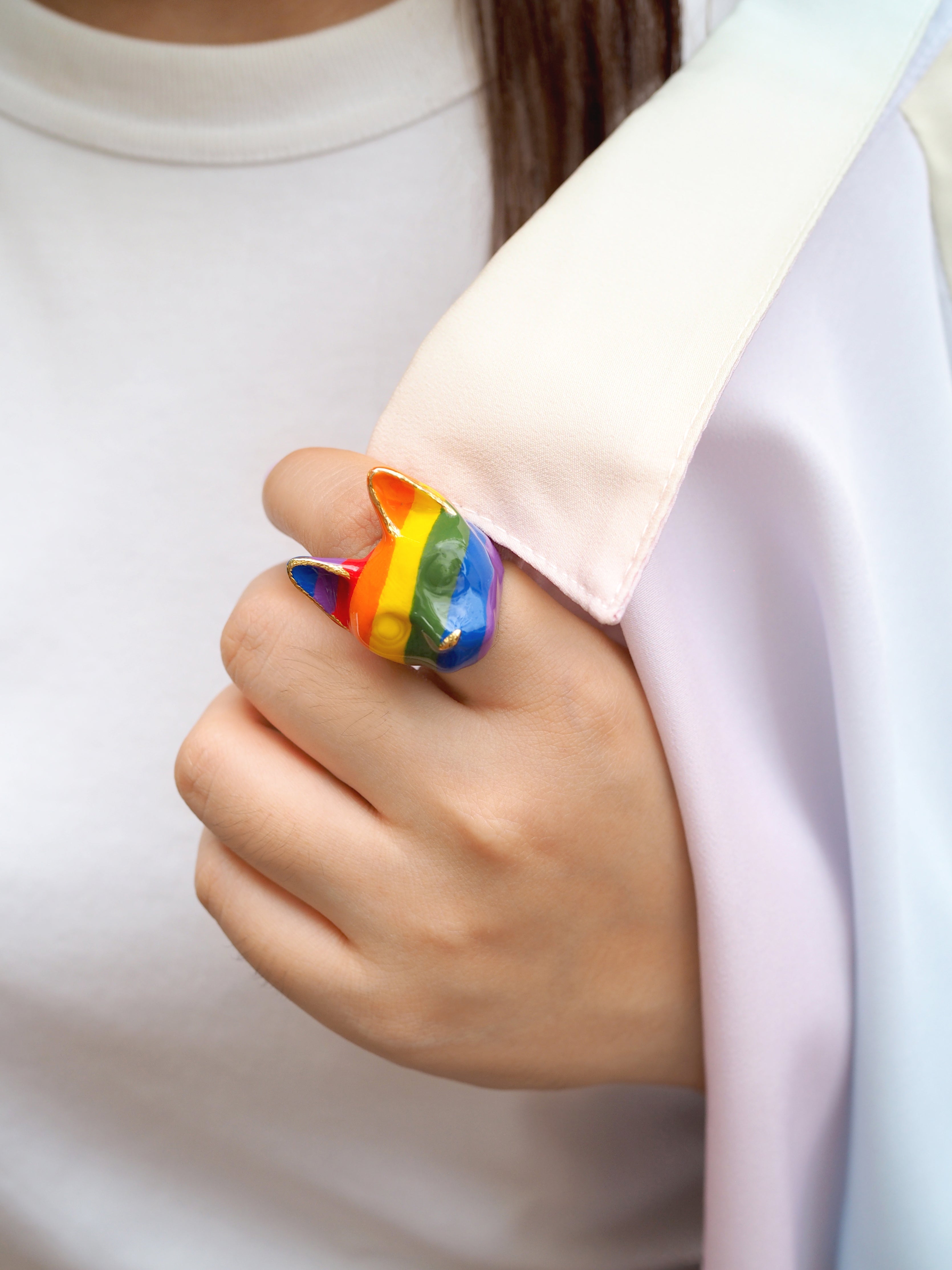 Close-up of a hand wearing a cat ring showcasing stripes with vibrant rainbow stripes