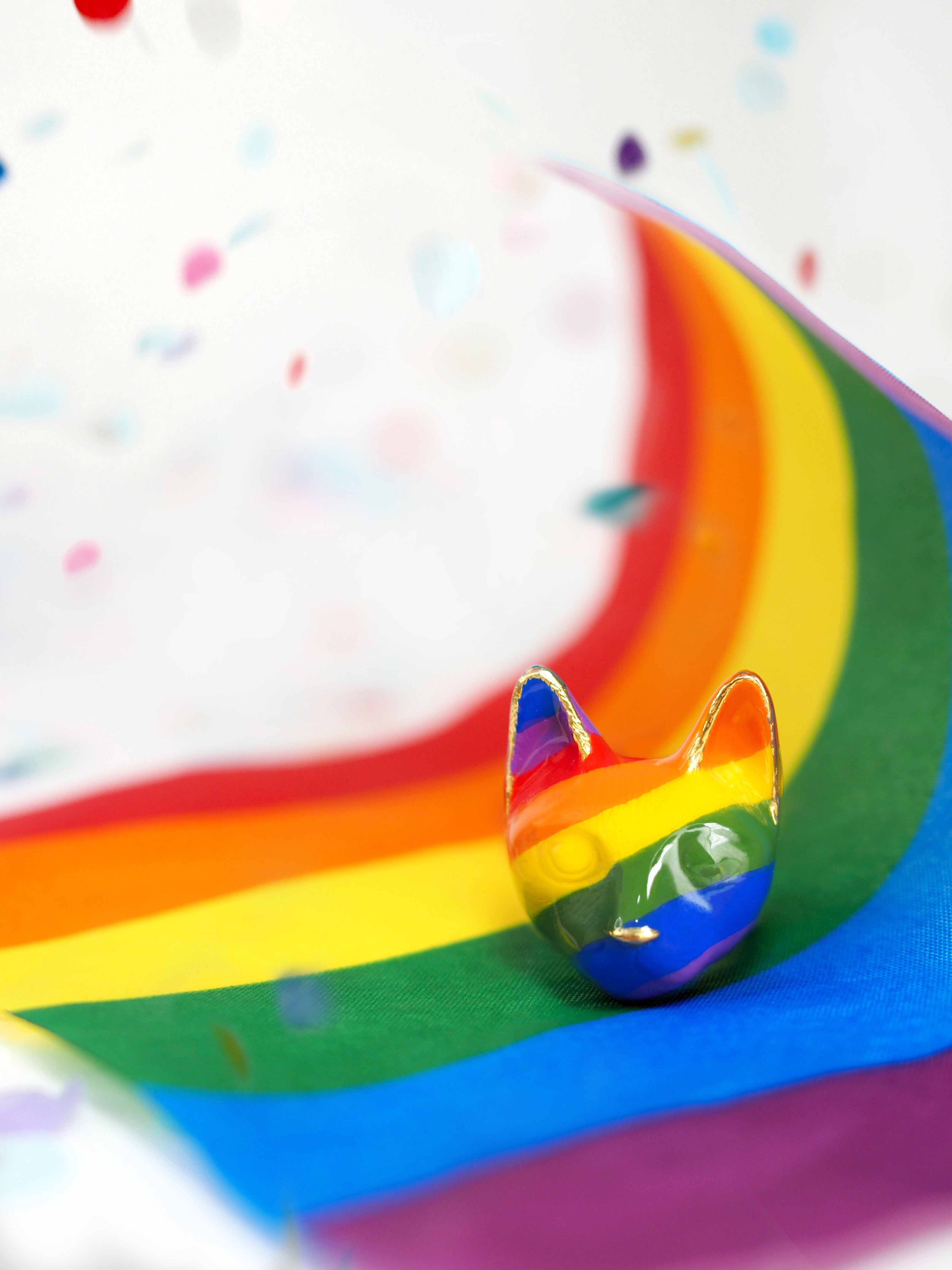 Close-up of a cat ring showcasing stripes with vibrant rainbow stripes placed on a rainbow flag