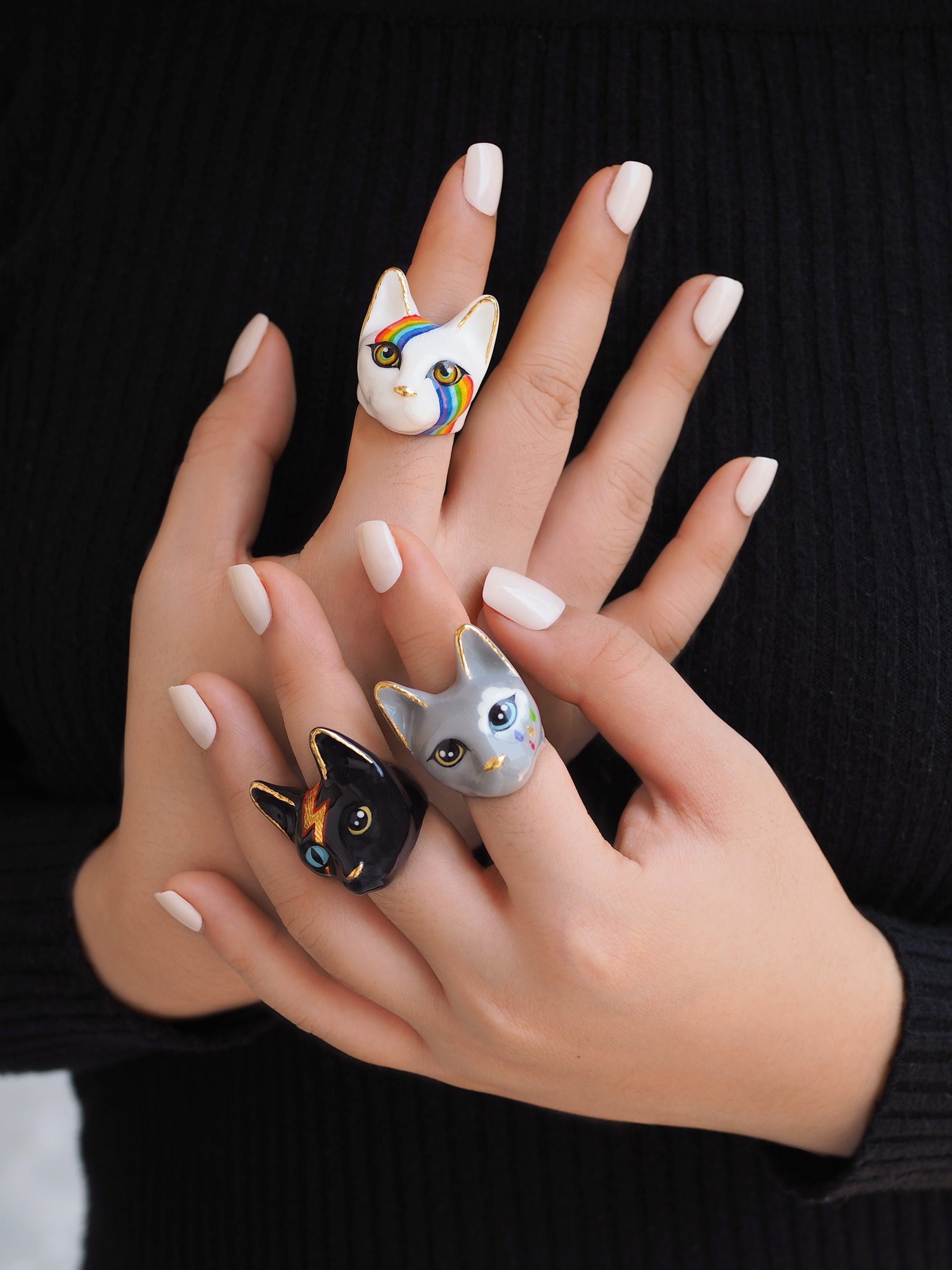 Collection of unique  cat rings showcasing designs on fingers.