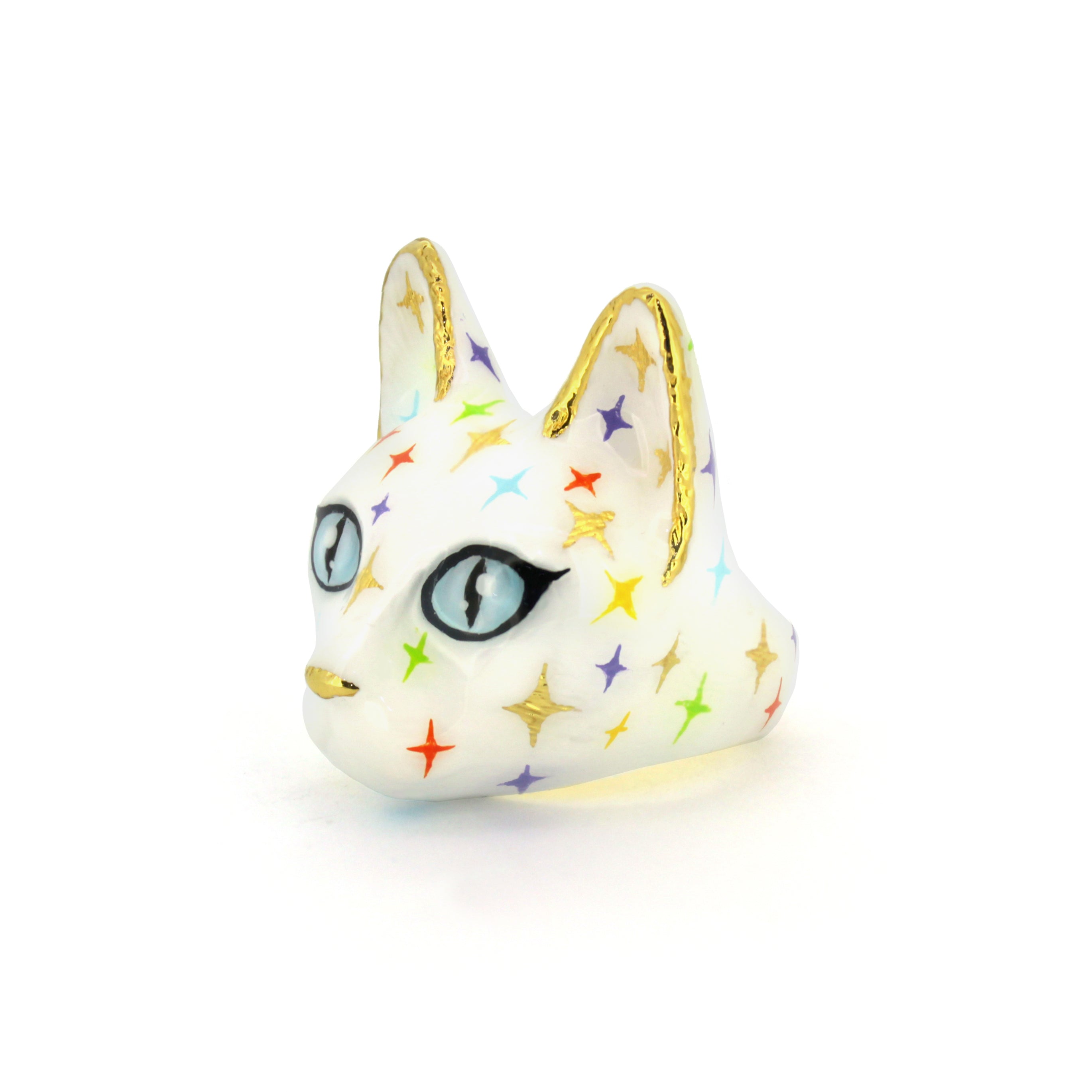 Whimsical cat head ring in white with blue eyes and gold accents, featuring multicolored twinkle patterns.