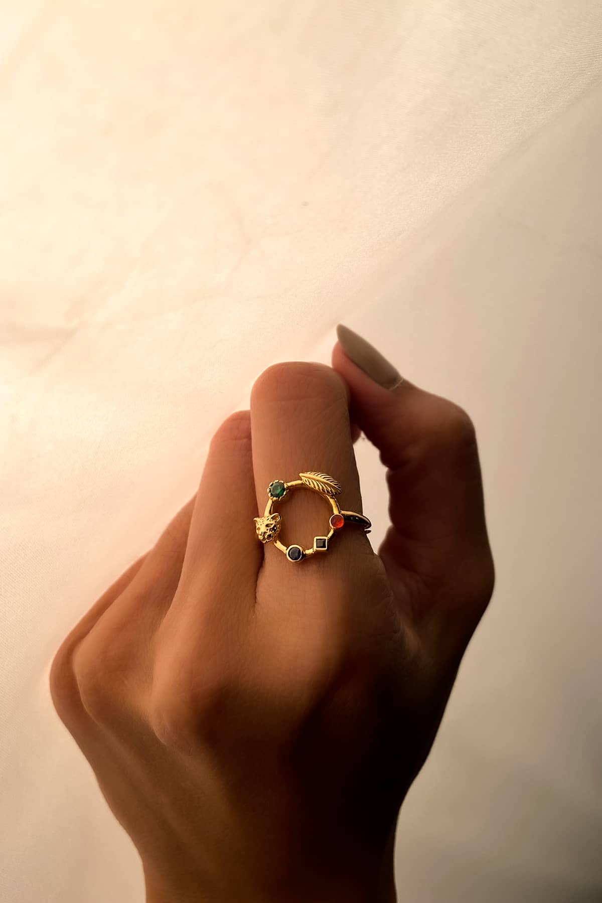 Close-up of an elegant gold ring featured leopard with colorful stones on a hand.