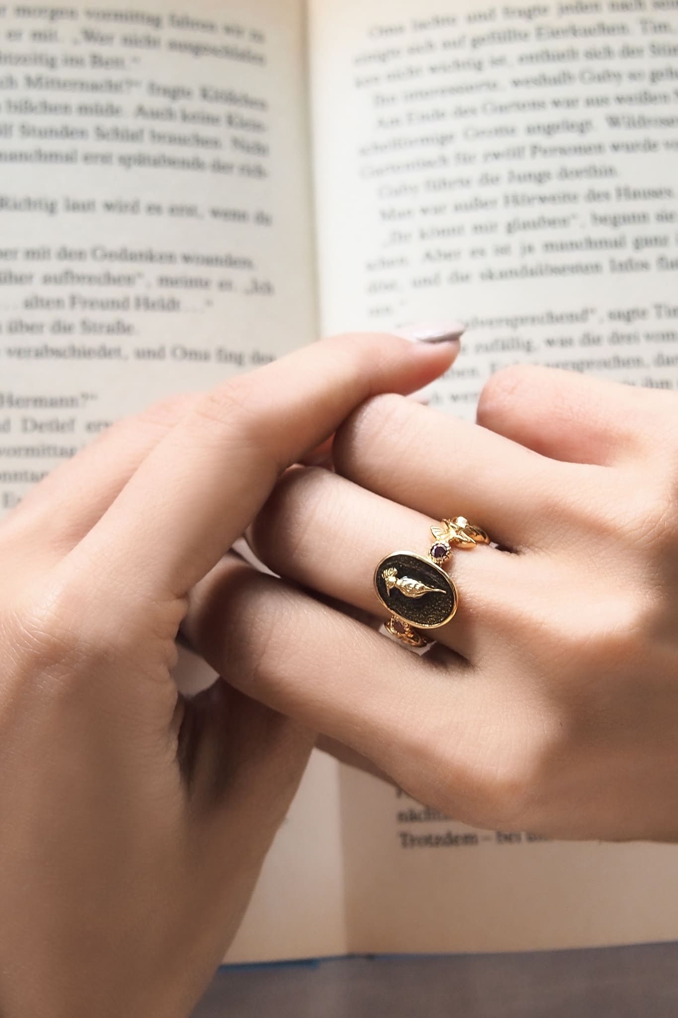 Close-up of a hand wearing an elegant gold ring featuring a hoopoe design.