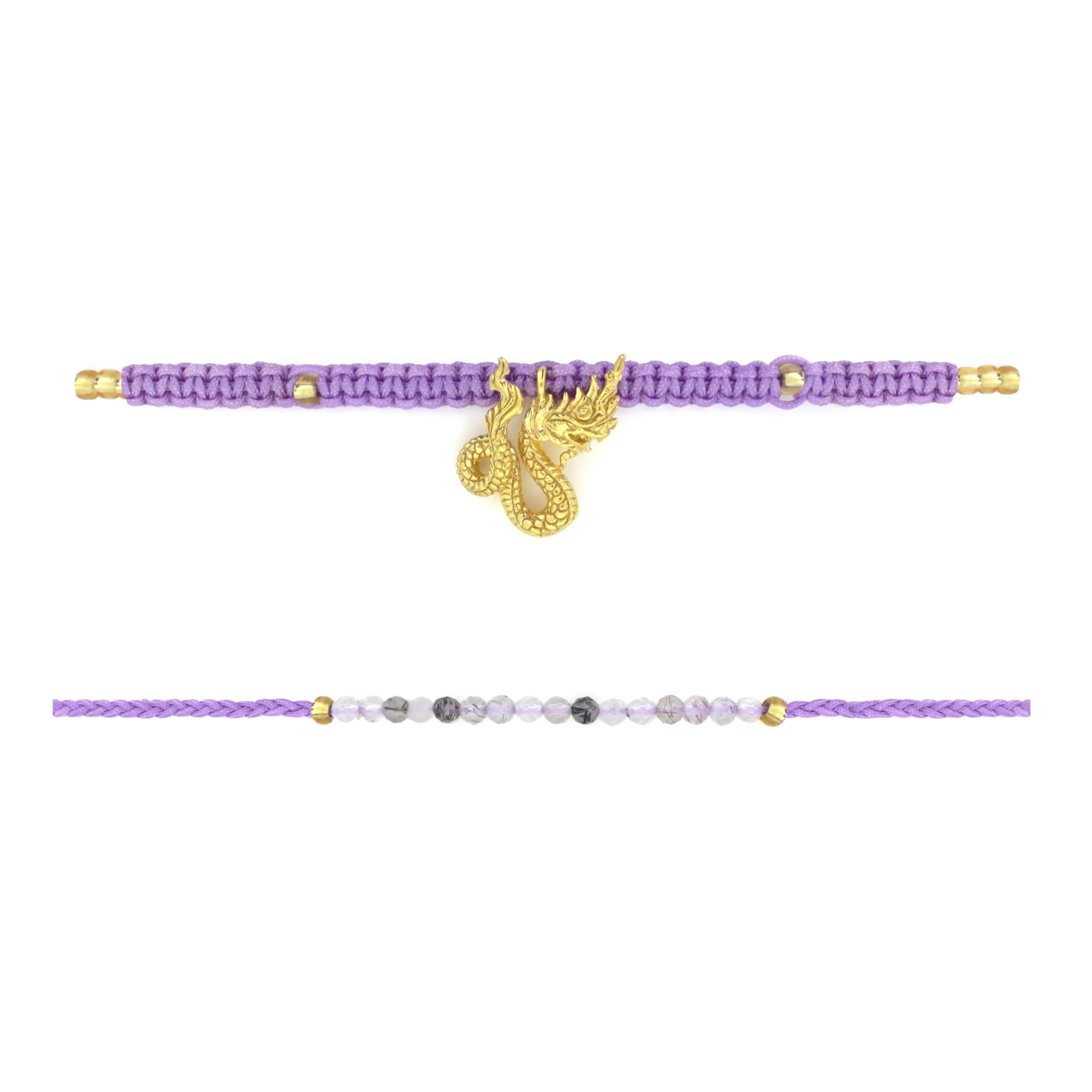 Set of two bracelets the top bracelet featuring a purple woven design material adorned with a gold Naga charm. The bottom bracelet features a series of grey and white beads with a simple woven purple band.