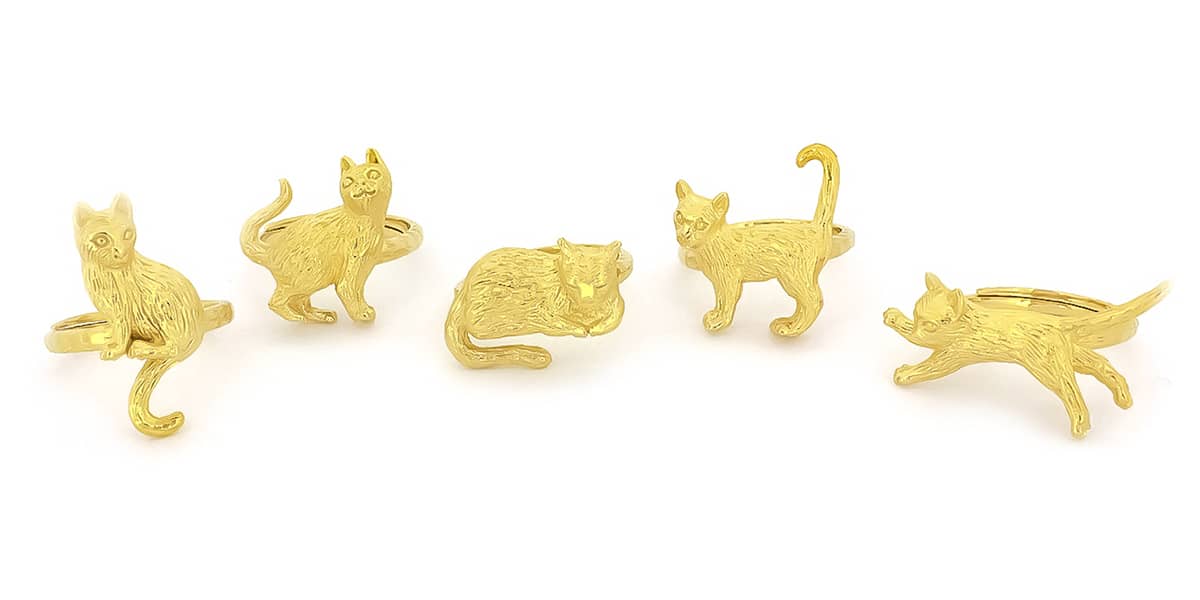 A collection of gold rings featuring playful cat designs in various poses, perfect for animal lovers.