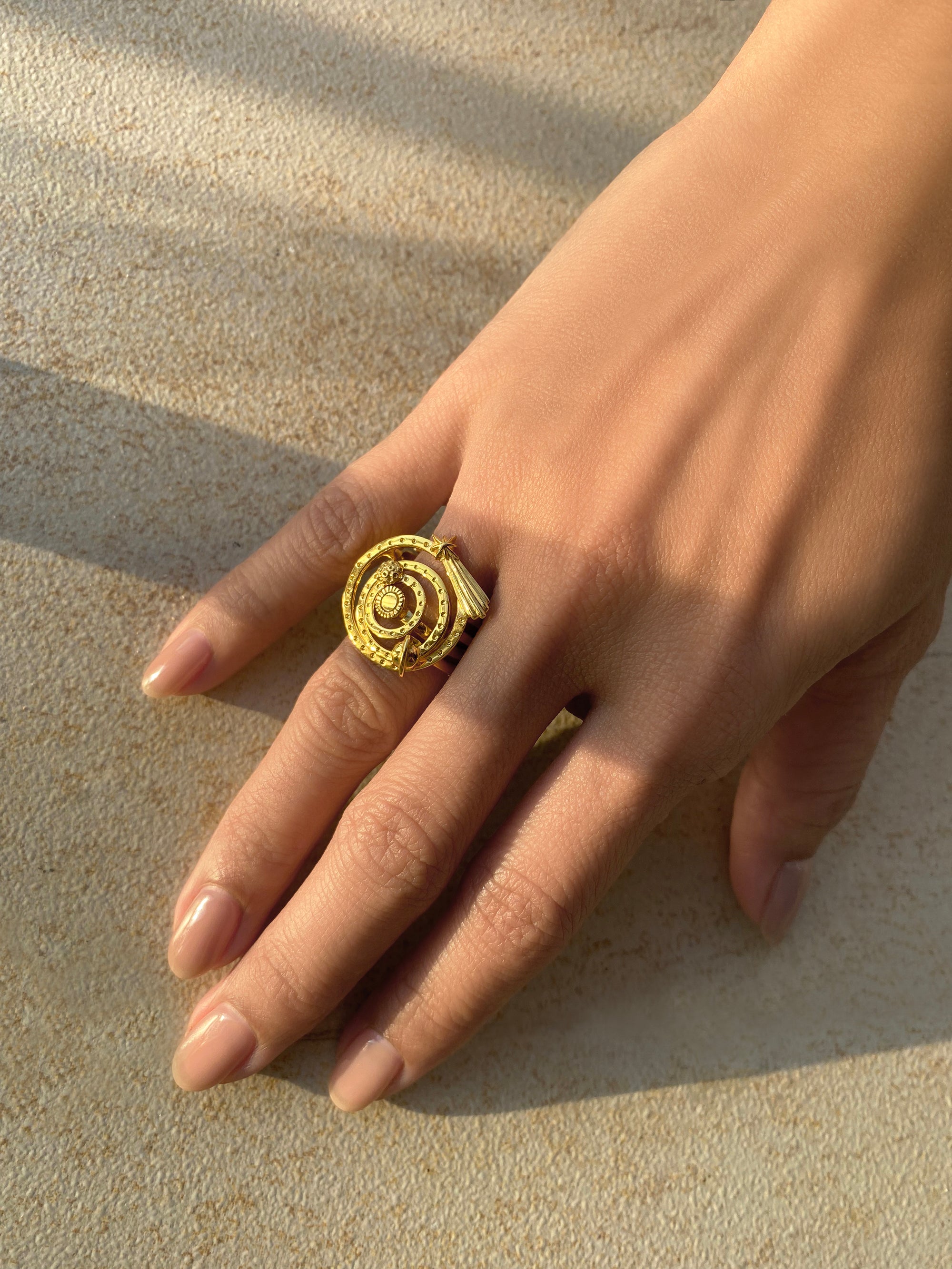 Close-up of a hand adorned with unique gold ring set, inspired by solar system.