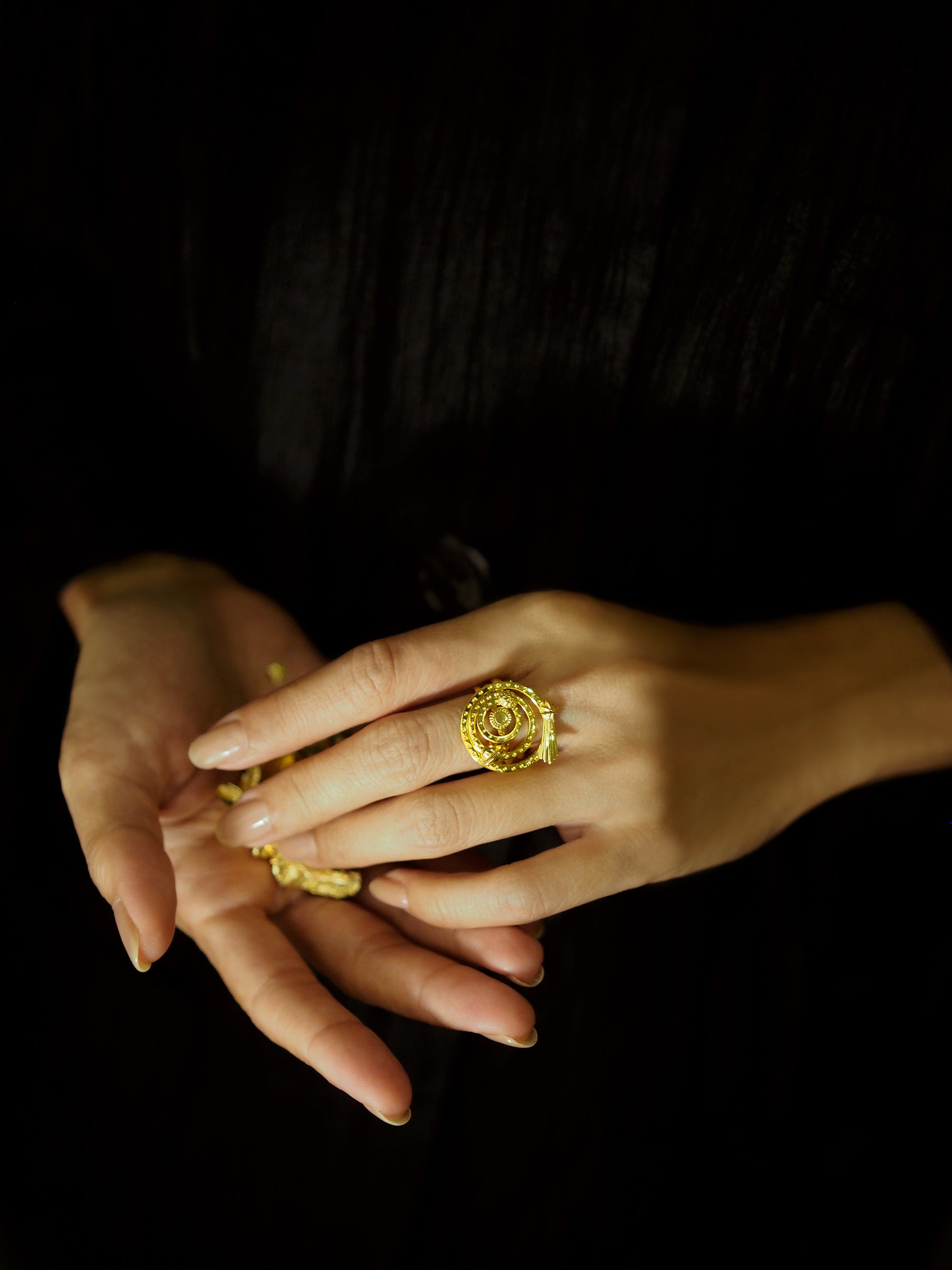 A close-up of a hand displaying a beautiful gold ring set with intricate designs and a smooth finish.