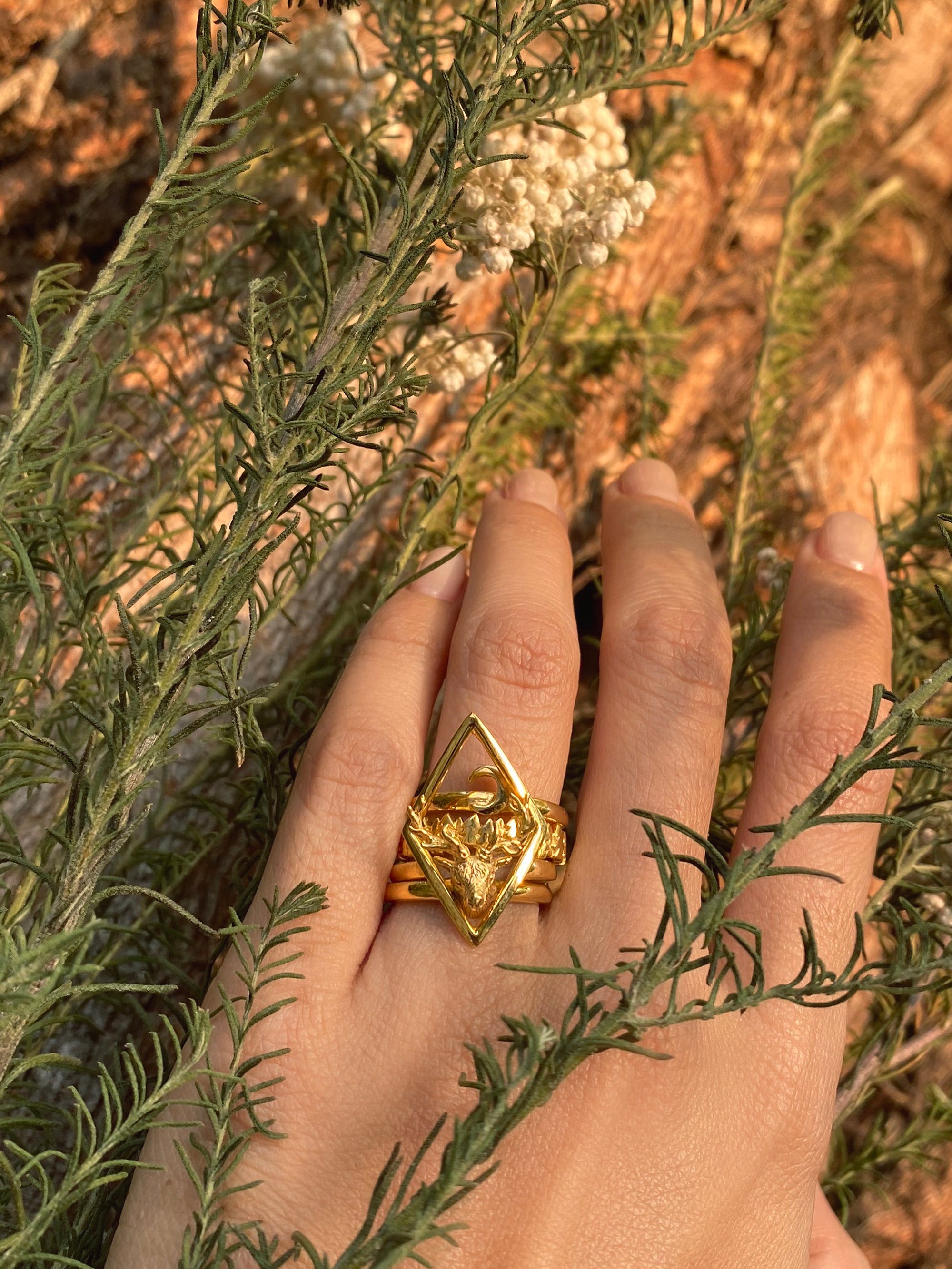 Nature-inspired stacking rings on a hand with a background of natural elements.