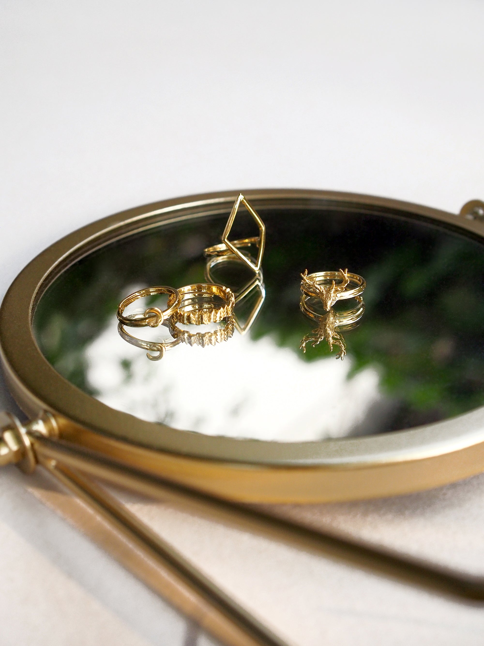 Close-up of gold stacking ring set reflecting on a mirror