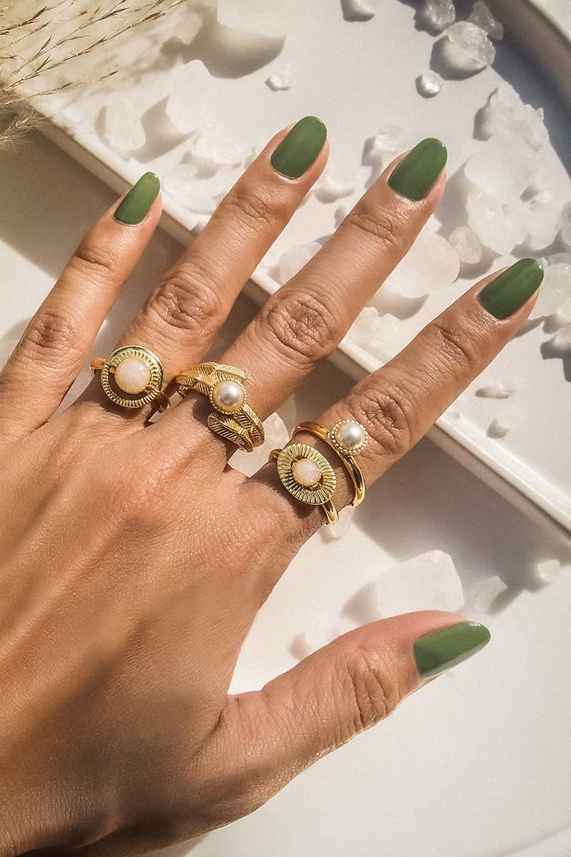 A collection of moon-inspired gold rings displayed on a plate with crystal ice.