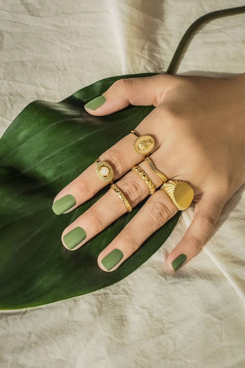 A close-up of a hand adorned with gold rings featuring moon and owl feather designs.