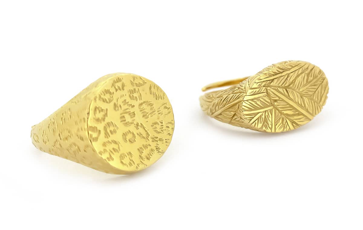 Two gold rings with distinct textures, one featuring a leopard print and the other a feather pattern.