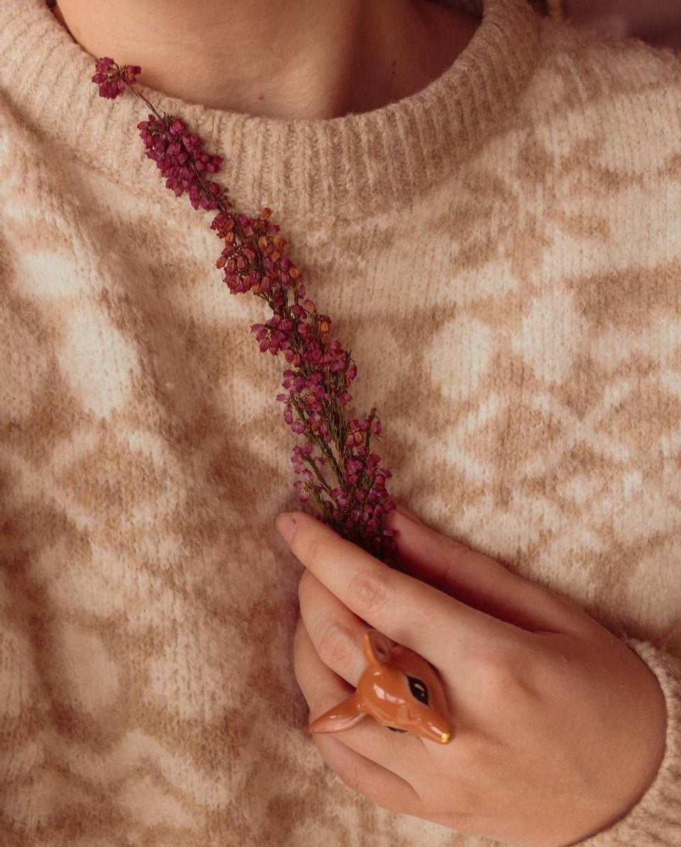 Nature-inspired deer ring worn by a person holding dried flowers.