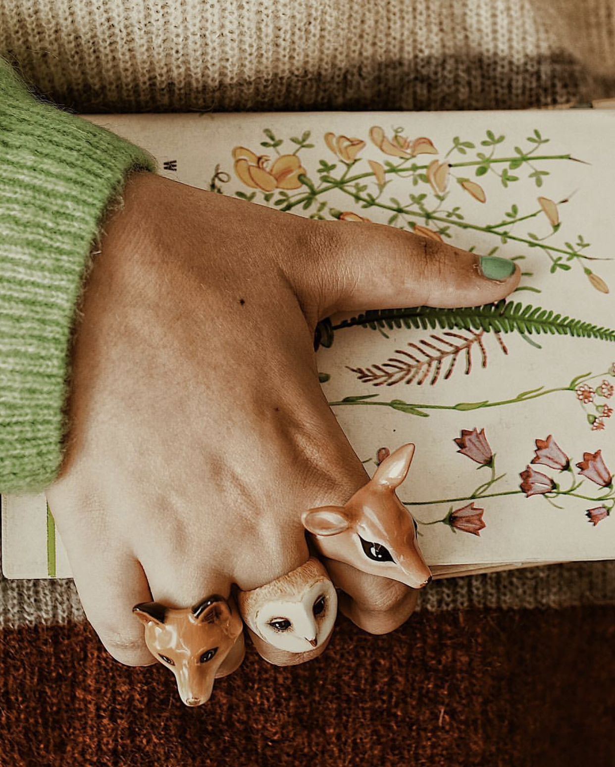 Close-up of animal rings including a fox, owl, and deer on a hand.