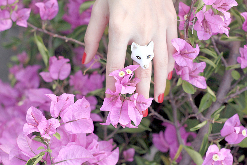 Close-up of a hand wearing a arctic fox surrounded by vibrant flowers.