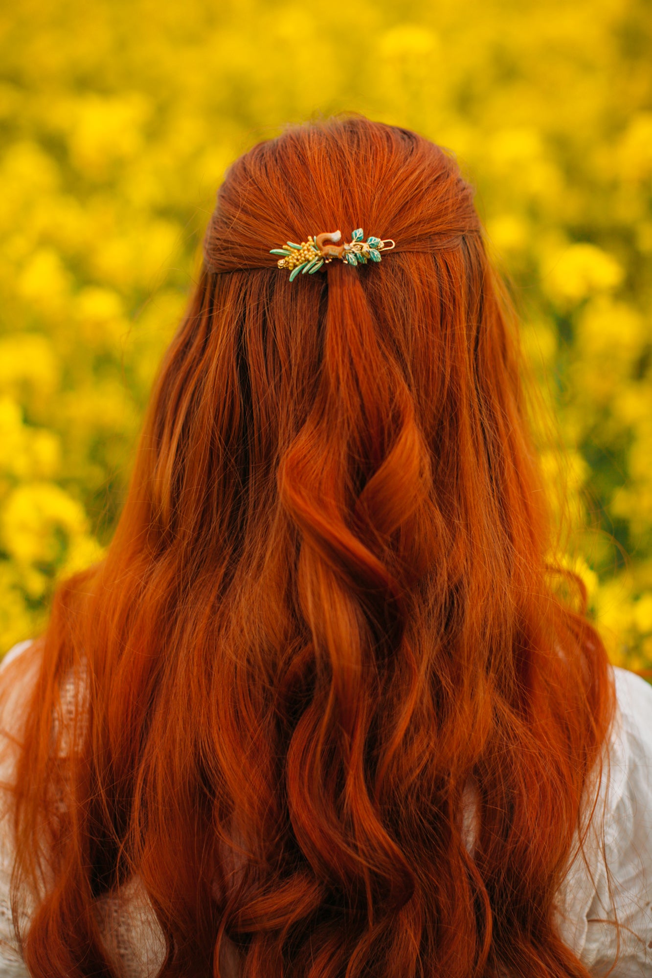 A stunning fox hairpin adorning red hair in a yellow flower field.