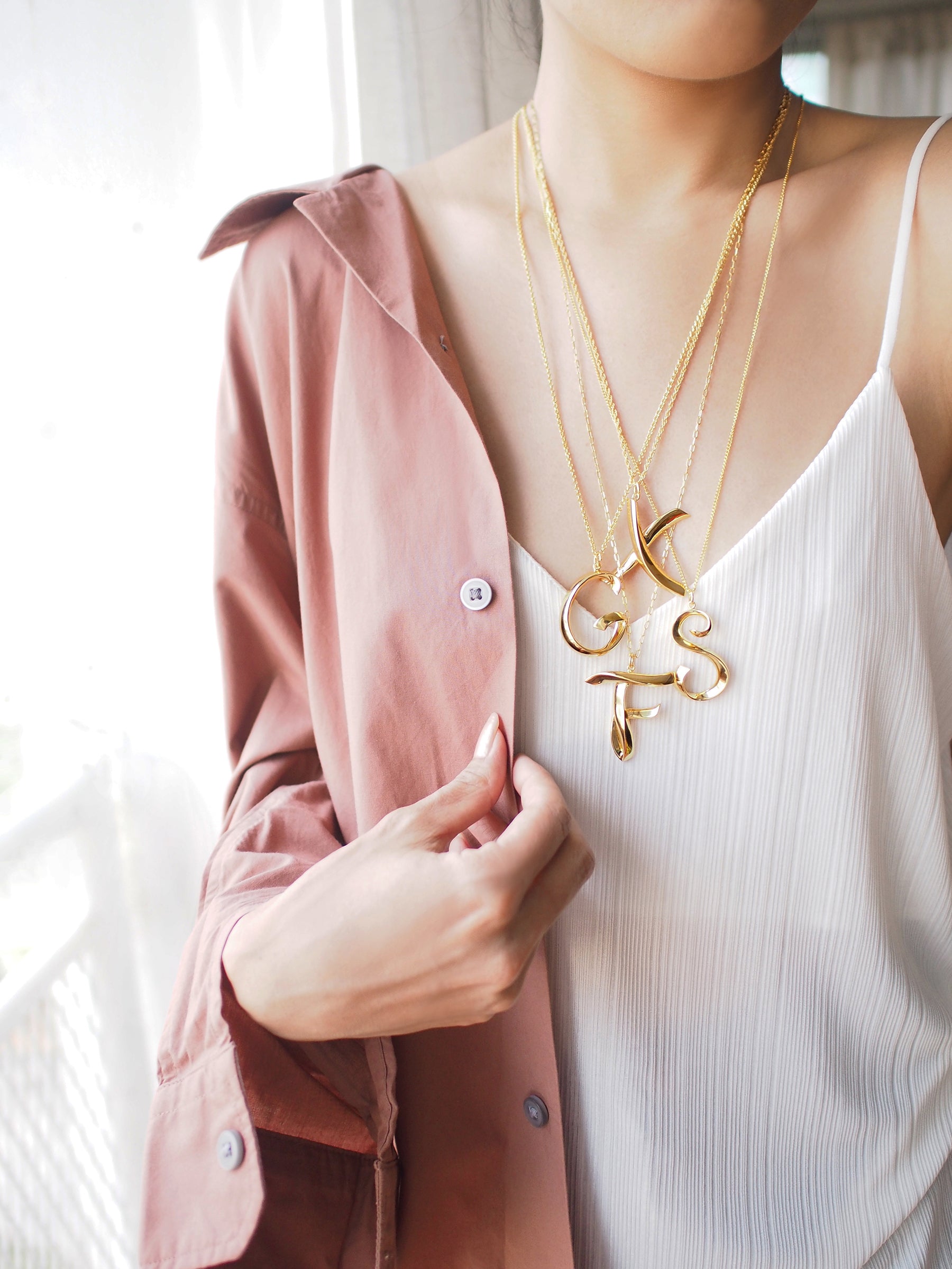 Close-up of fashionable layered letter necklaces on a woman.