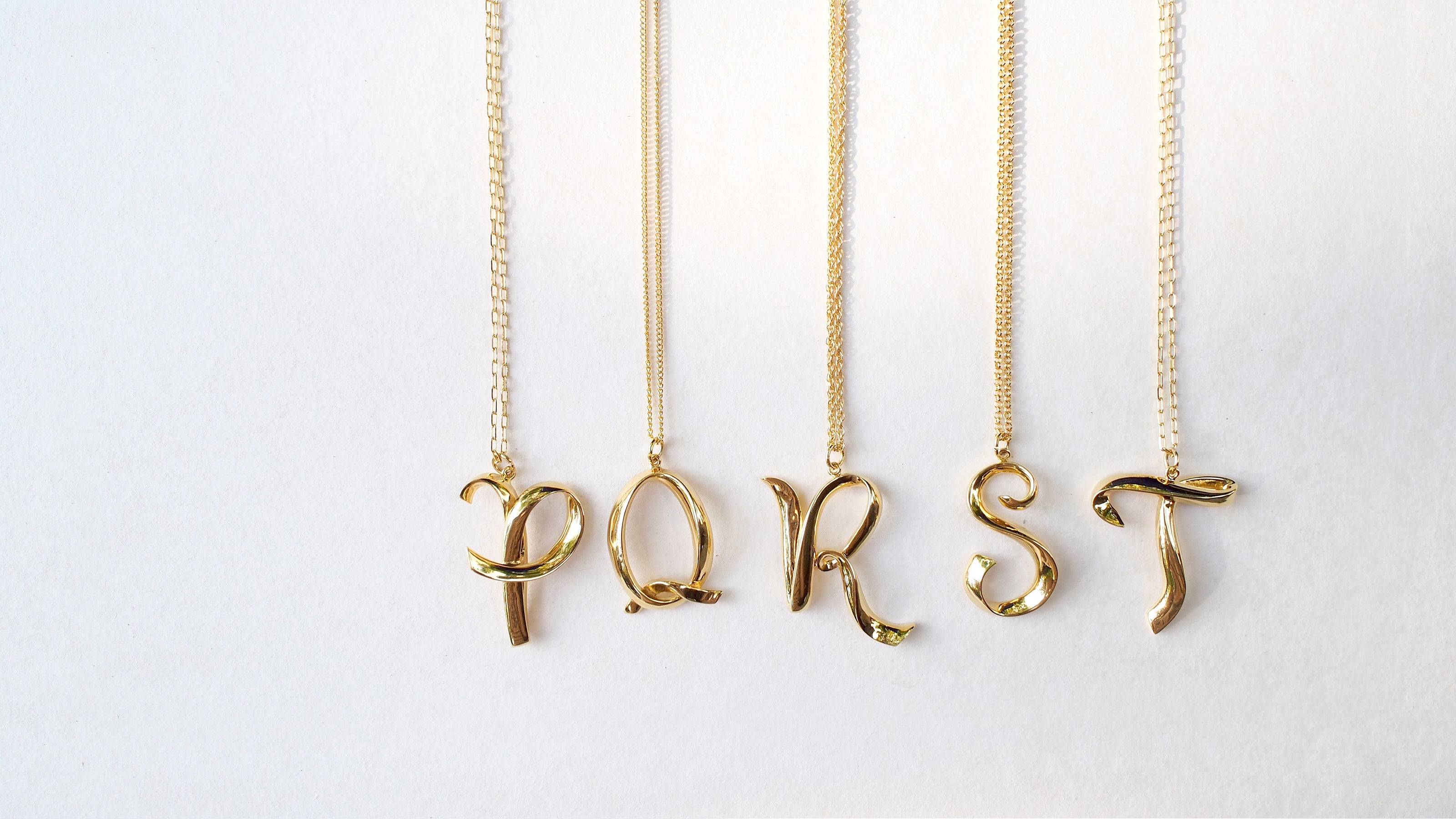 Gold-colored necklaces with charming letters P, Q, R, S, and T on various chain styles, perfect for fashion lovers.