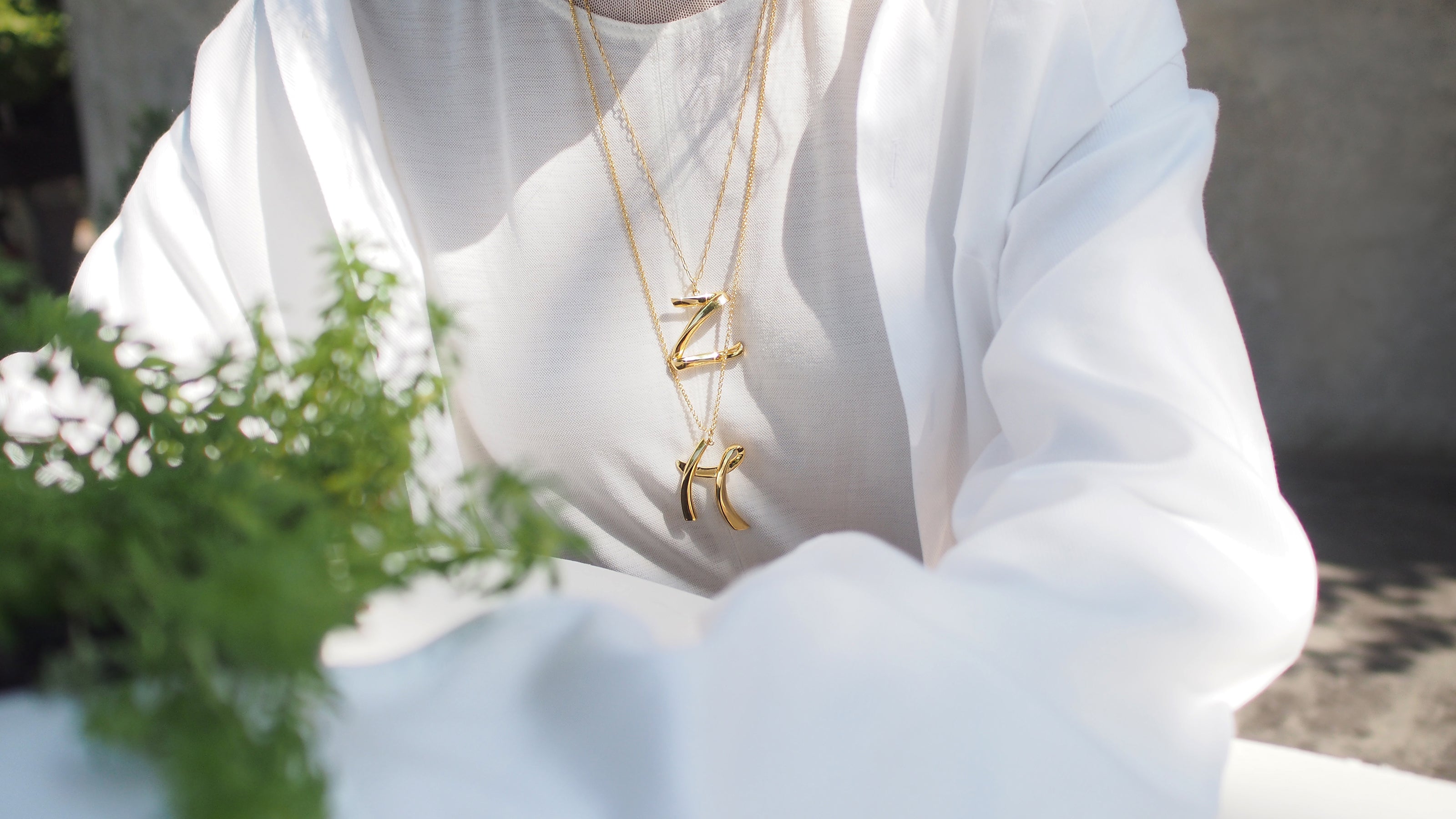 Stylish gold-colored initial necklaces worn by a model.