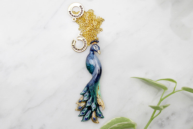 Charming peacock pendent necklace with intricate feather details on a gold chain, perfect for animal lovers.