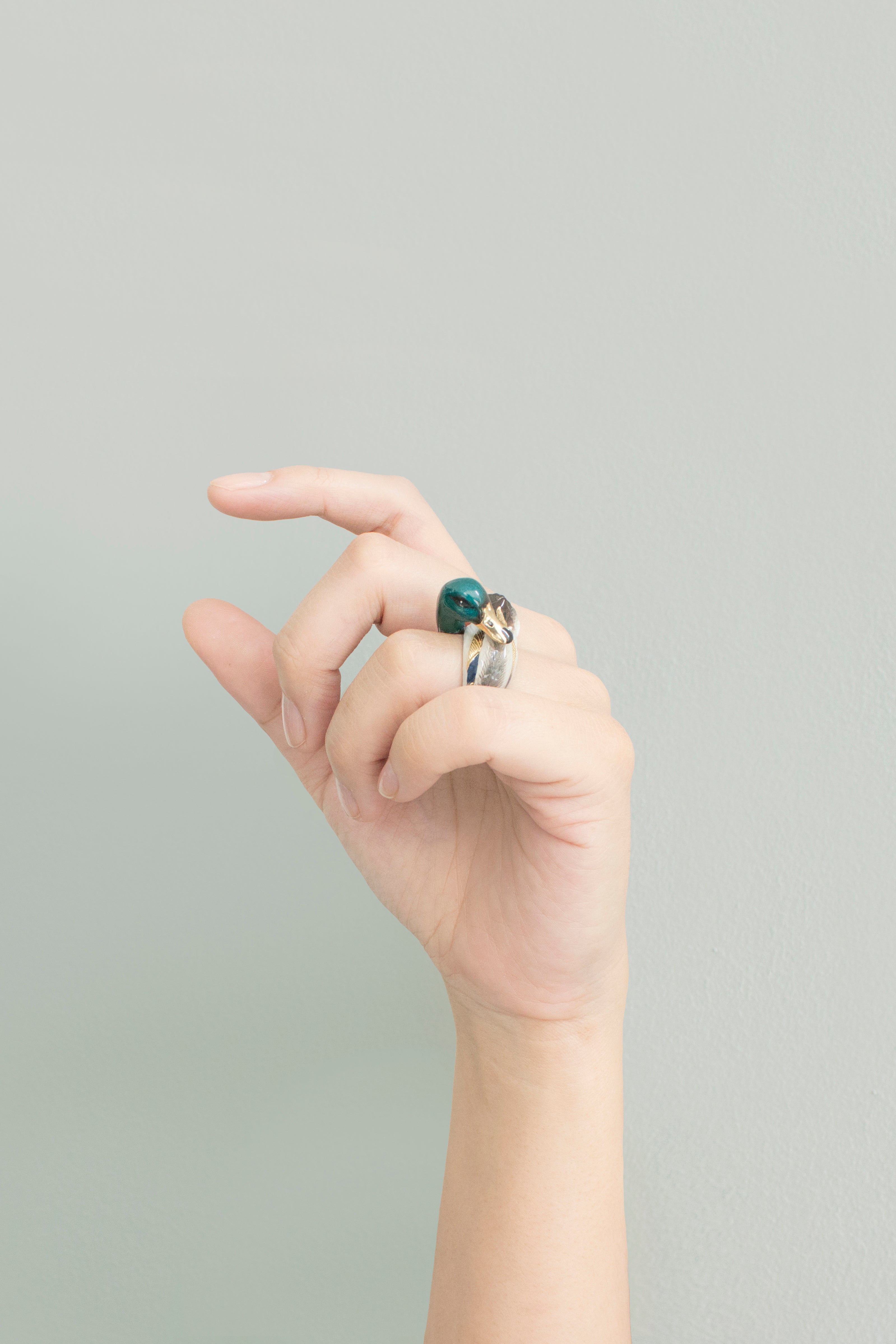 Close up of a unique mallard duck ring worn on a finger.