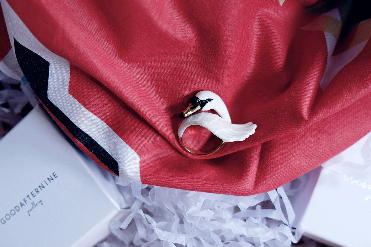 A close-up of a beautiful swan ring placed on a red fabric.