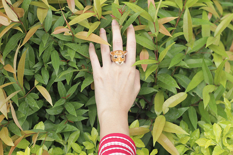 Unique tiger face ring showcased on a hand in a natural setting.