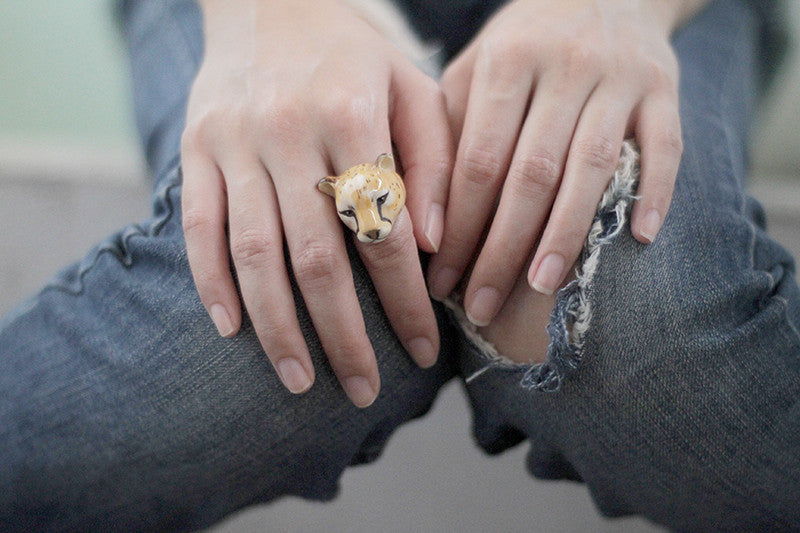 Close-up of an animal-inspired ring featuring a cheetah's face displayed on a casual outfit.