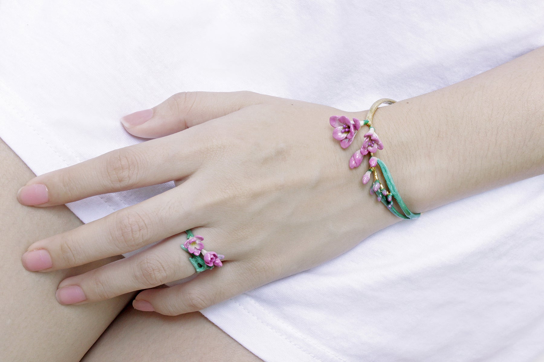 Close-up of a hand wearing a pink flower ring and matching bangle.