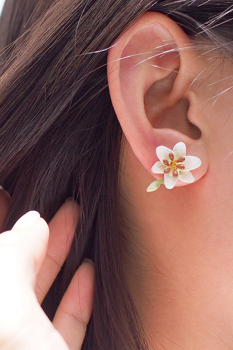 A close-up of a woman's ear adorned with a flower earring, ideal for summer fashion.