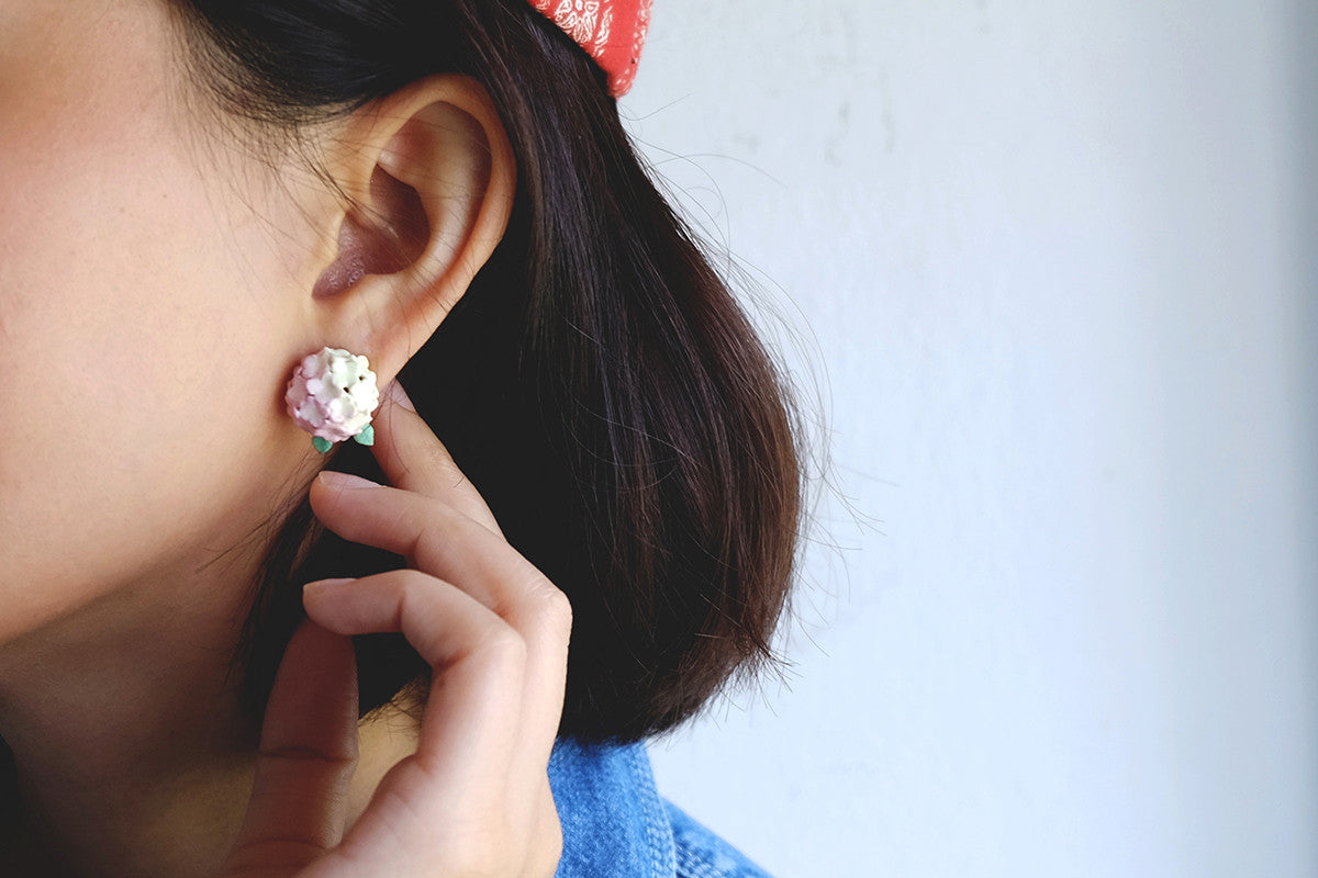 Close-up of hydrangea-themed earrings worn by a model.