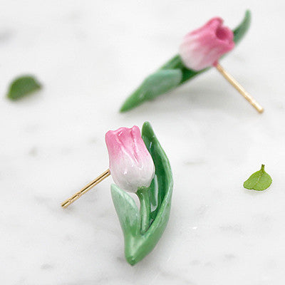 Charming floral earrings featuring pink tulip and green leaves, placed on a marble background.