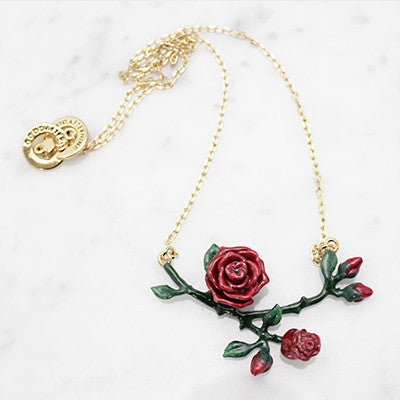 Beautiful floral necklace featuring red roses and green leaves on a gold chain.