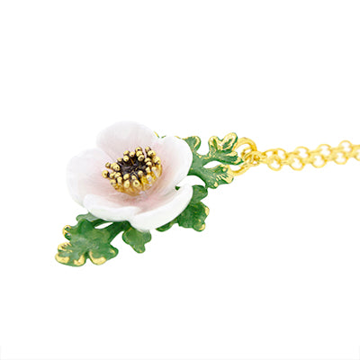 Light pink, white flower pendant and green leaves on a golden necklace.