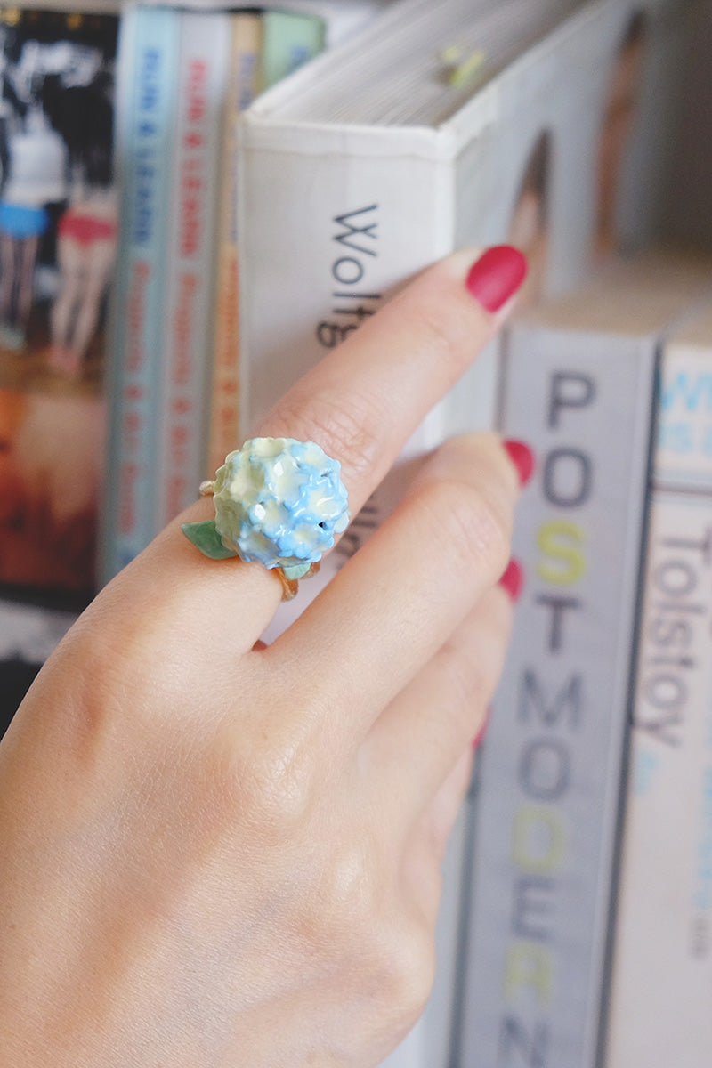 A close-up of a hand wearing a blue hydrangea flower ring