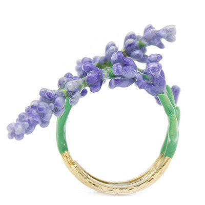 A handmade gold ring featuring delicate lavender flowers and green leaves, curved around the band.