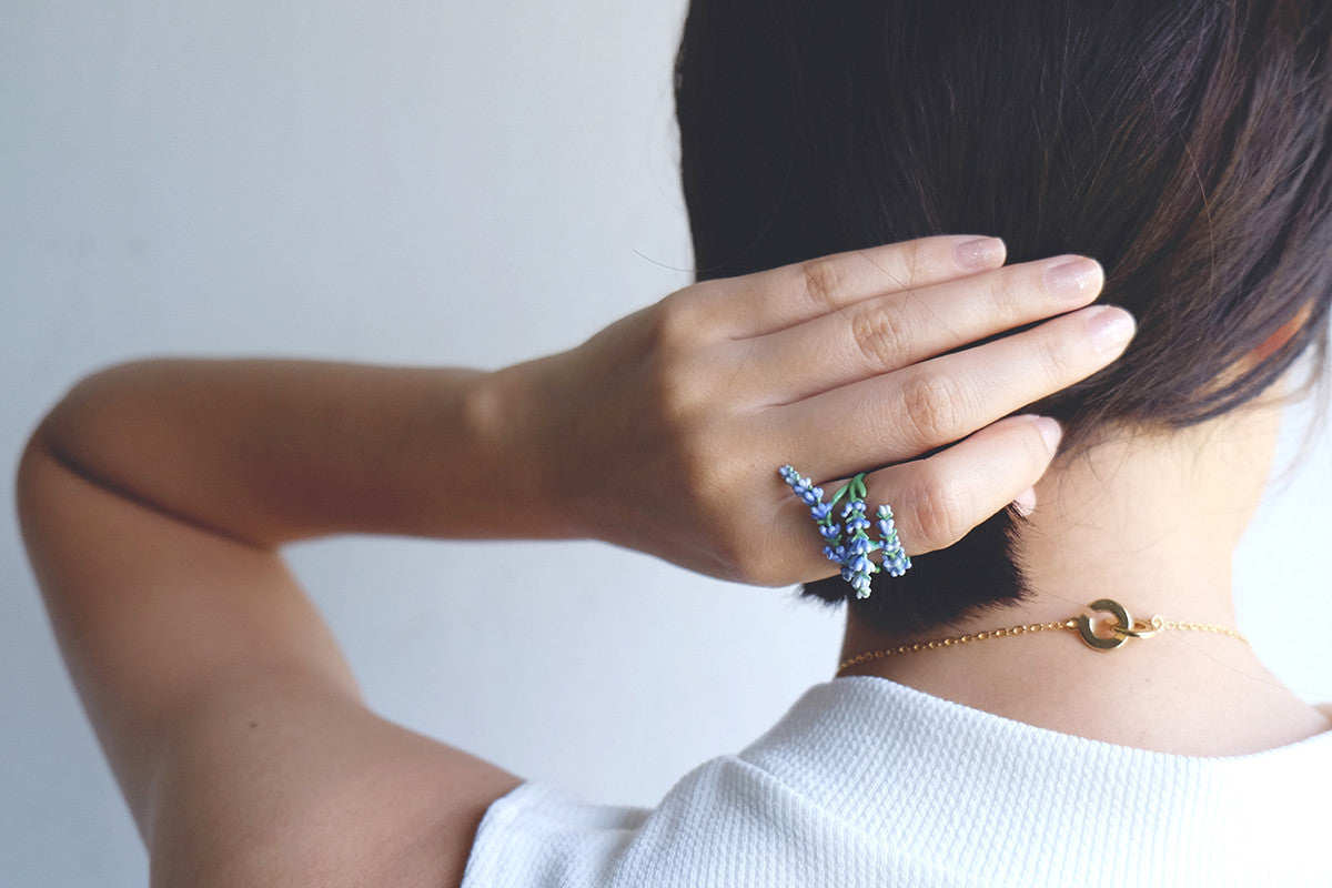 A close-up of a hand with lavender ring with a casual outfit.