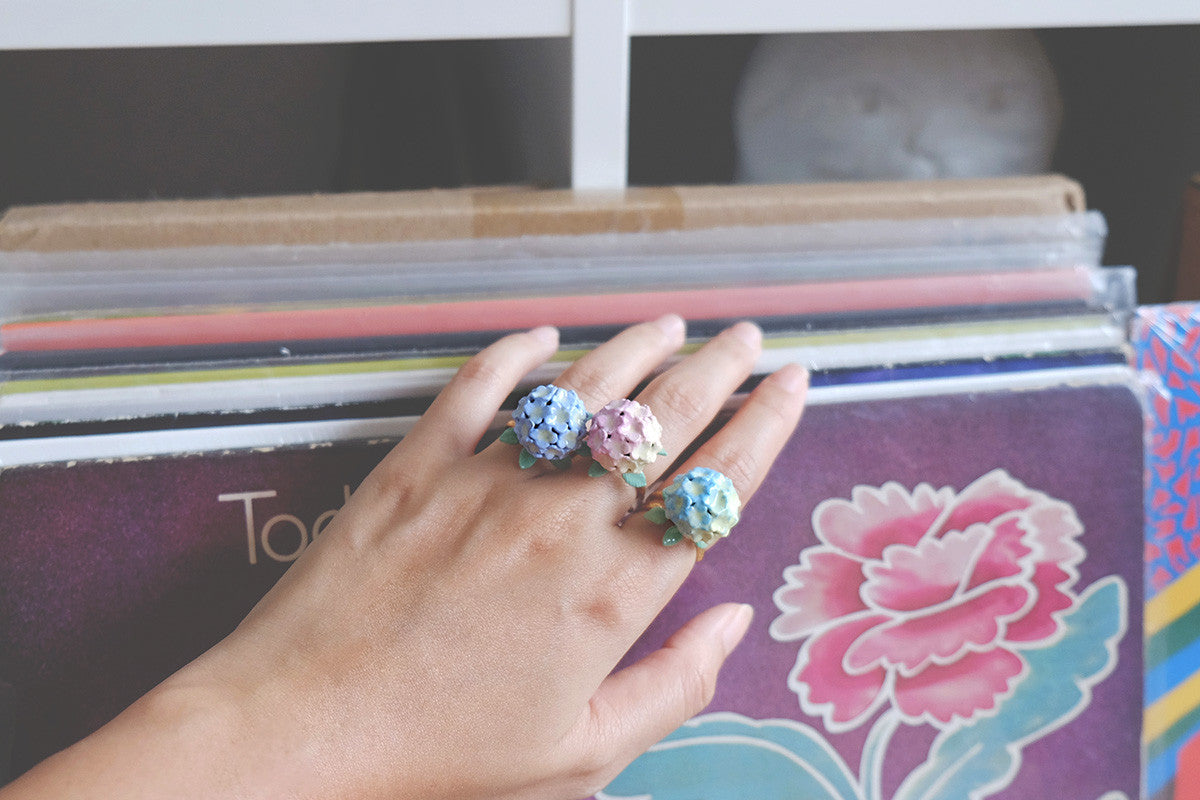 Close-up of colorful hydrangea rings on a hand against a background of vinyl records.