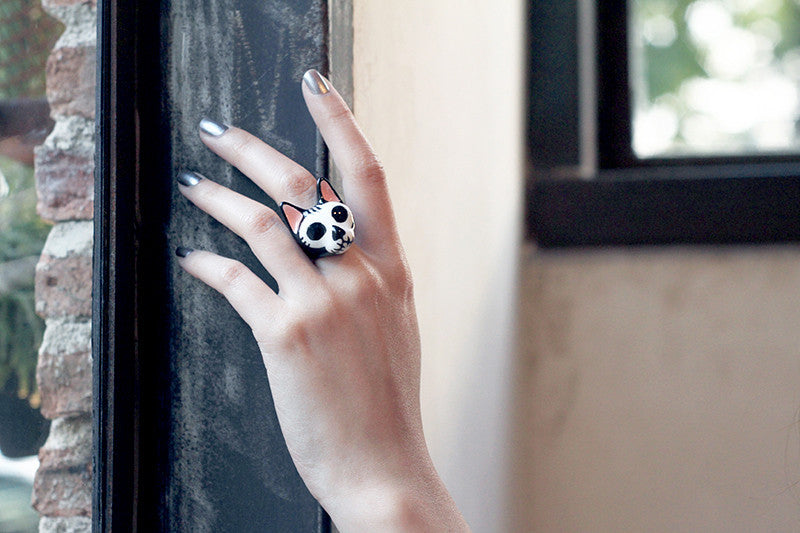 Close up of a hand showcasing a cat ring with skull design in black and white color.