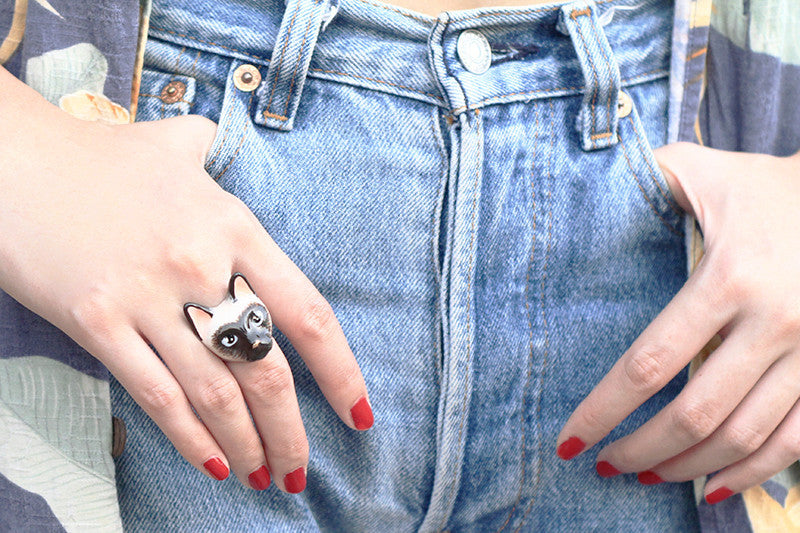 Close-up of a unique cat ring on a woman's hand, paired with casual denim attire.