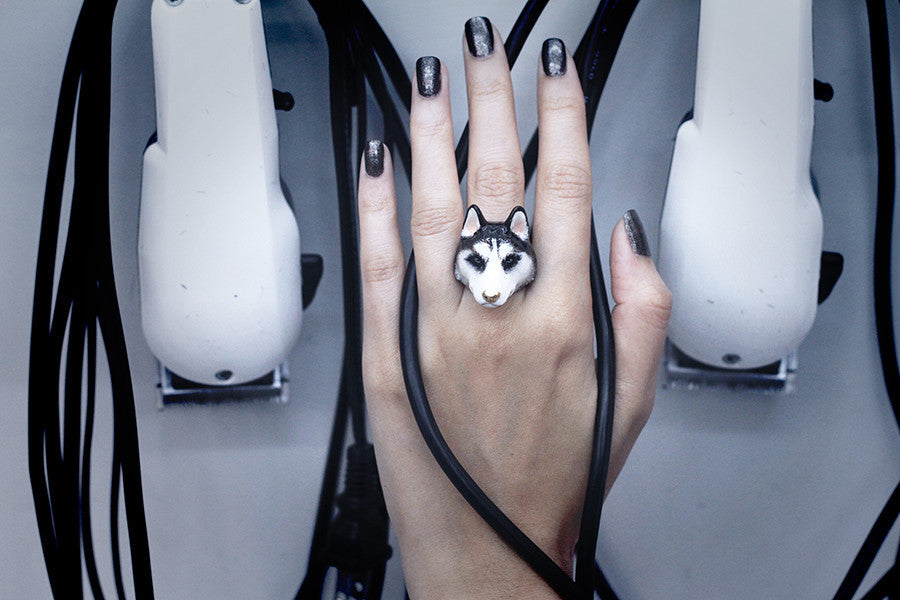 Close-up of a hand wearing a husky-shaped ring with black nail polish.