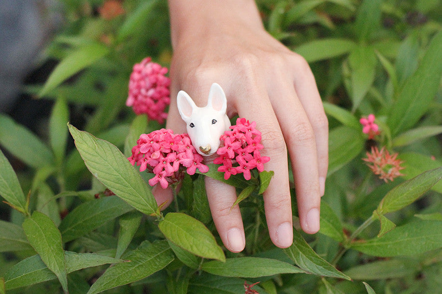 Close-up of a bull terrier ring on a hand among vibrant flowers.