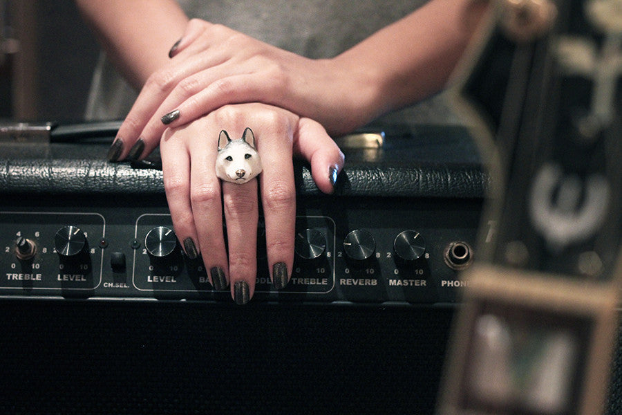 A hand with a Siberian husky ring rests on a black amplifier.