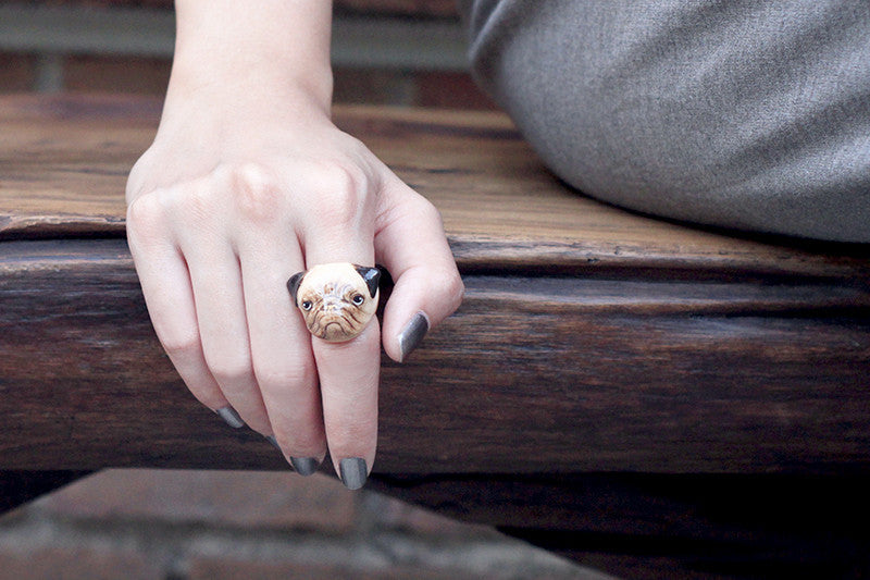 Close-up of a hand wearing a handcrafted dog ring featuring pug design