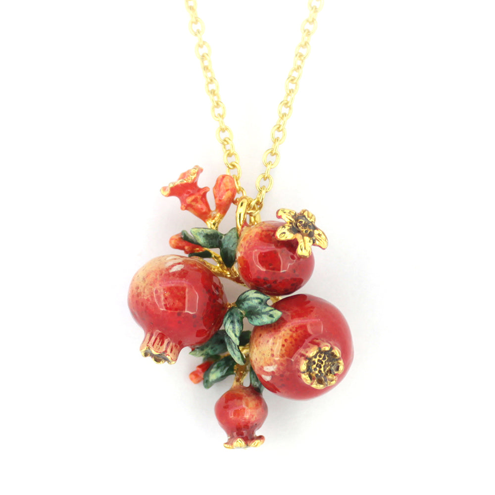 A golden chain necklace featuring three intricately crafted pomegranates surrounded by green leaves and tiny red flowers.