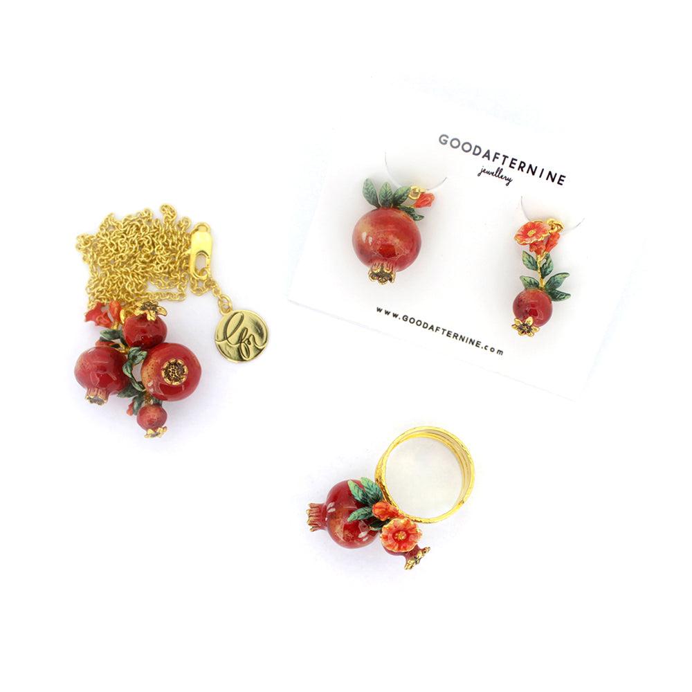 Collection of charming pomegranate ring, earrings, and necklace adorned with delicate red flowers and green leaves.