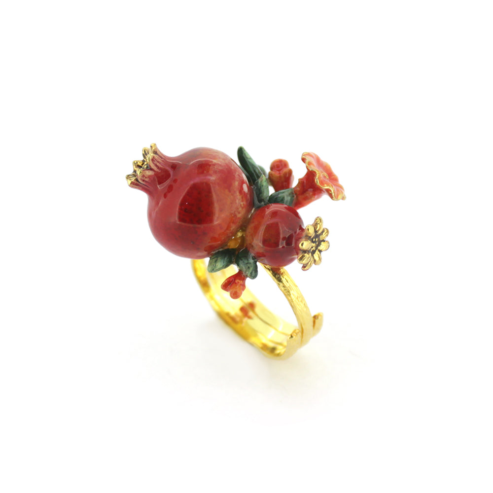 A charming gold ring featuring two pomegranates, green leaves, and small red flowers, embodying a vibrant, nature-inspired design.