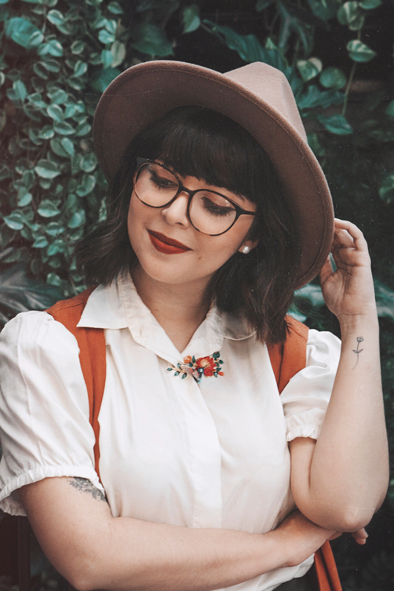 Outdoor portrait of a woman showcasing her hummingbird necklace.